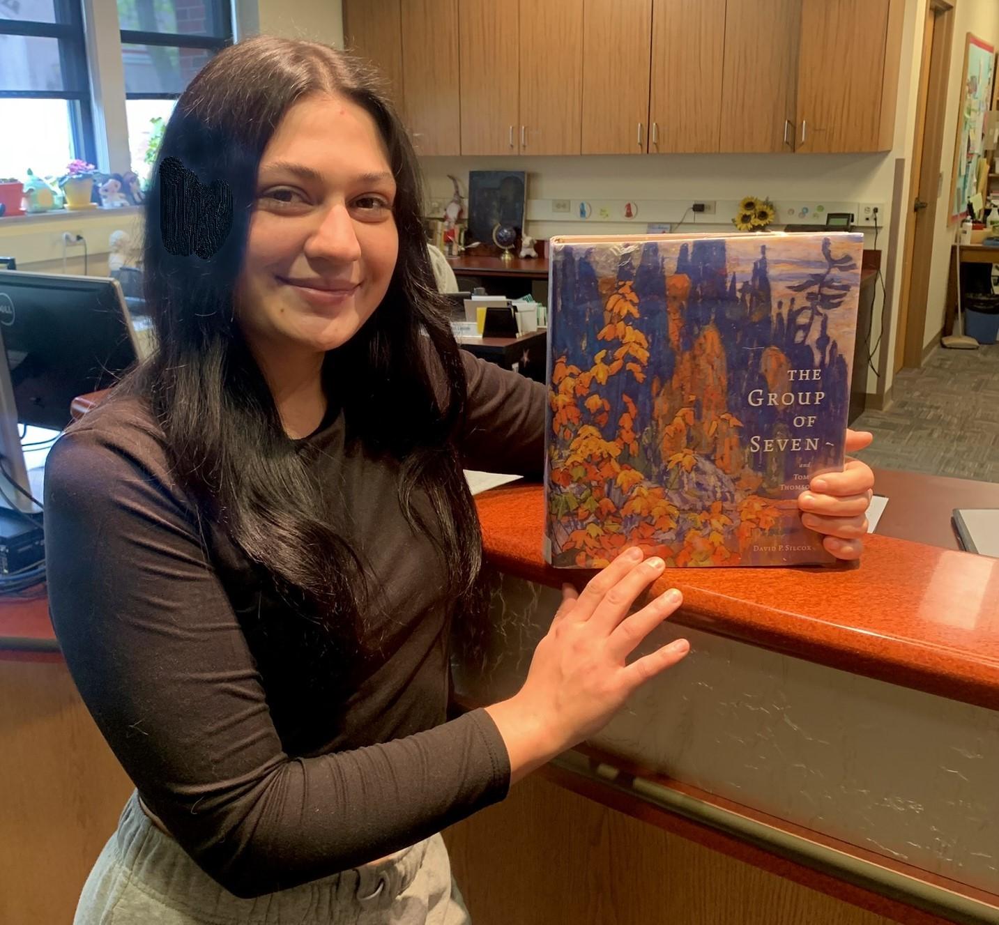 Gretchen Cortez holding the book The Group of Seven and Tom Thomson
