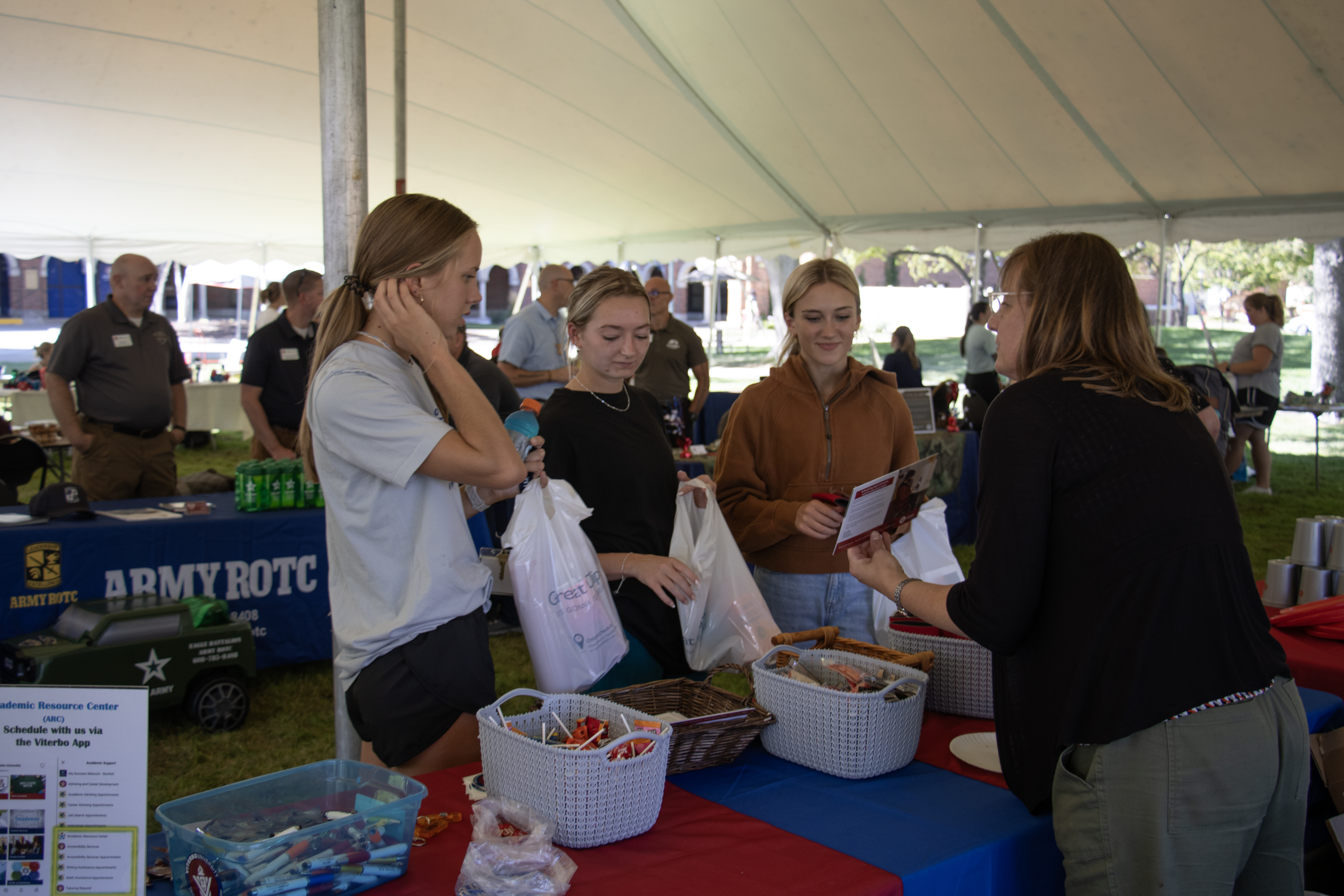 Image of three students stopping at a table for Welcome Back Bash. 