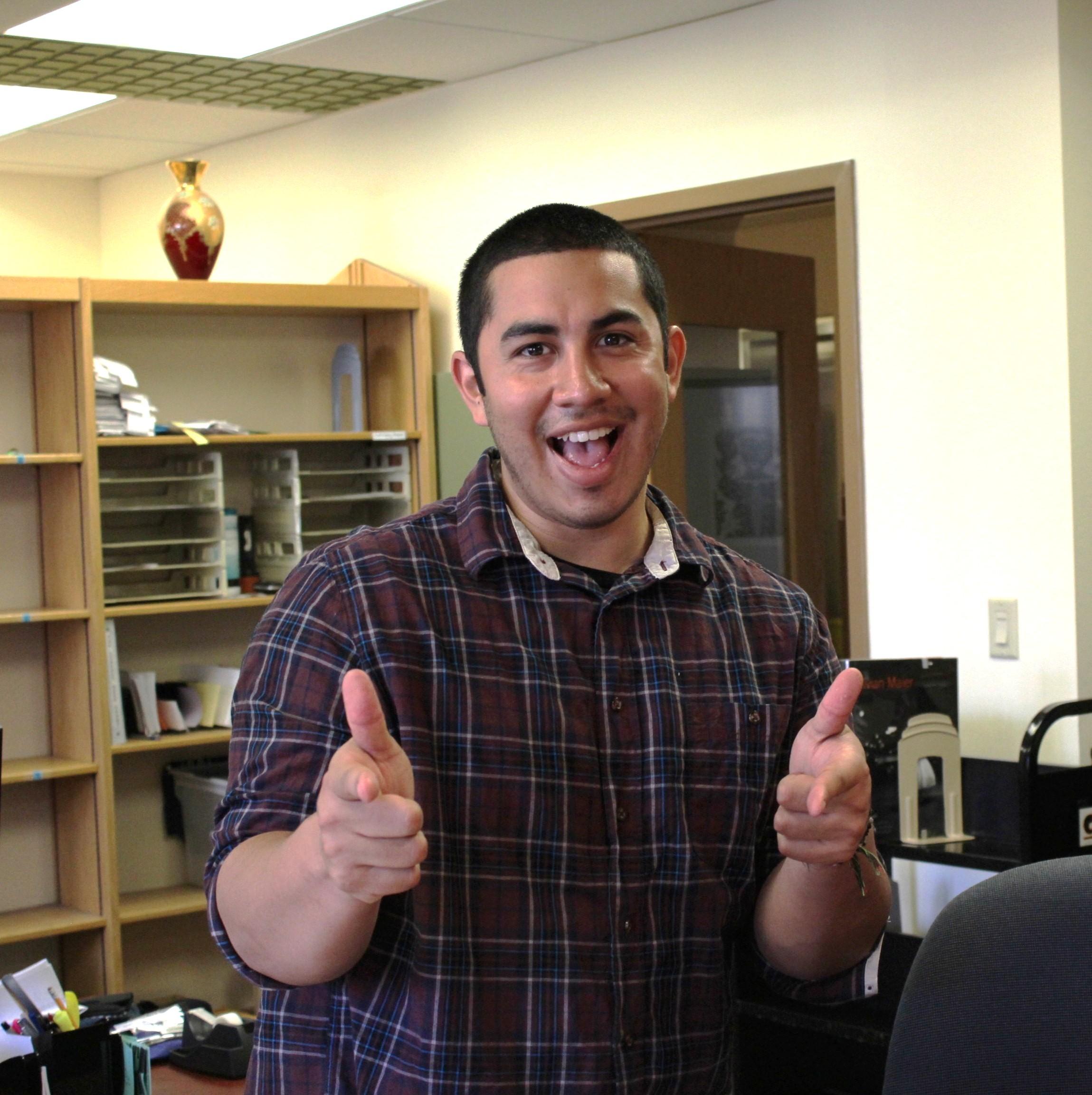 Male student worker with two thumbs up at the Library's Circulation Desk