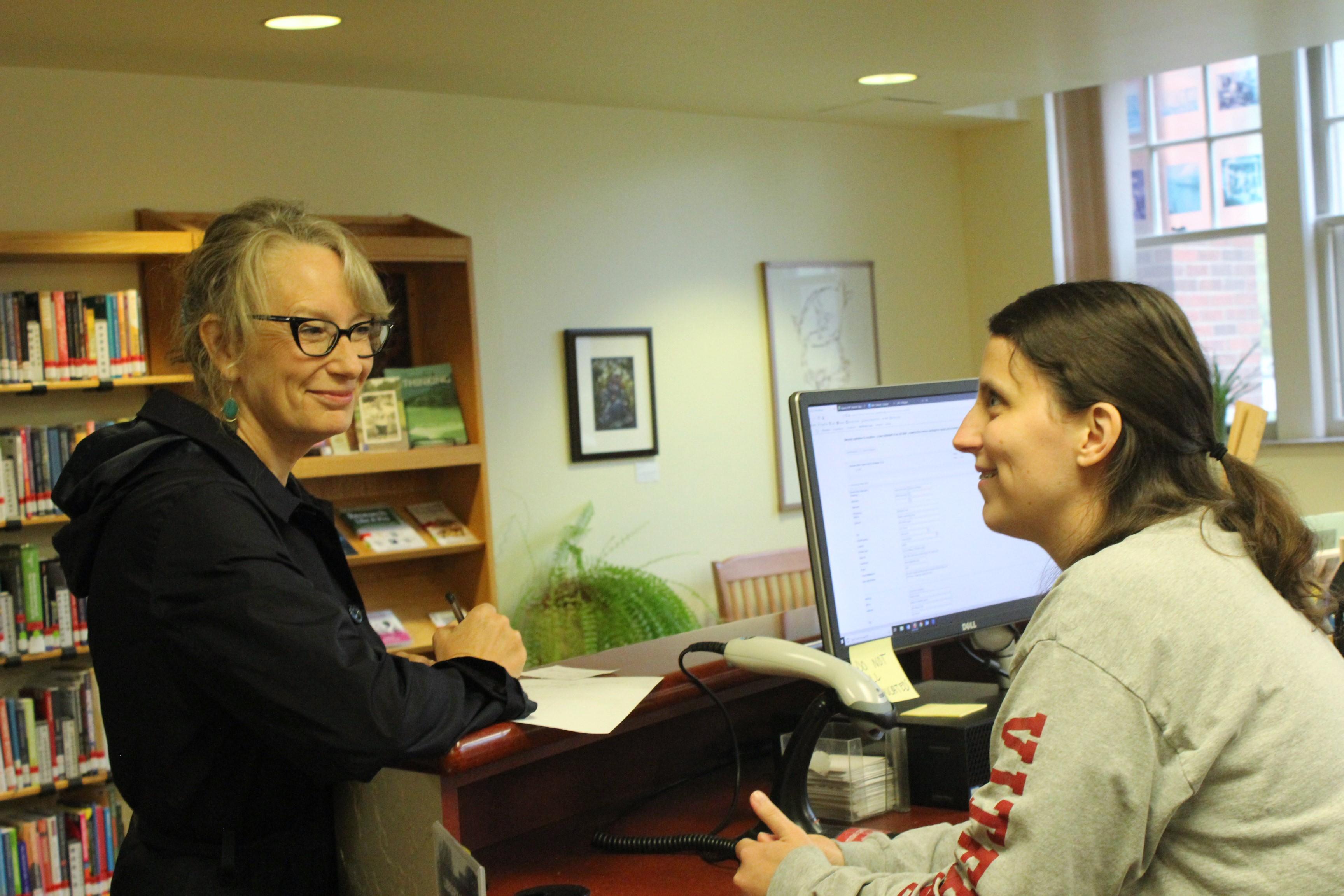 Caitlyn Konze helps a student at the circulation desk