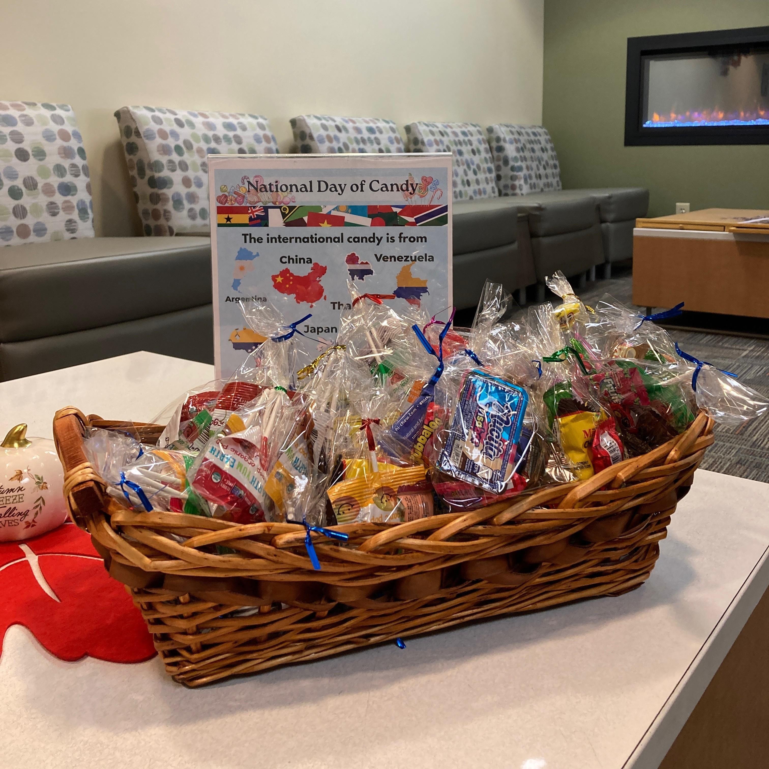 Photo of a basket full of bagged candies in front of a sign reading, "National Day of Candy" and "The international candy is from China, Venezuela, Argentina, Thailand and Japan."