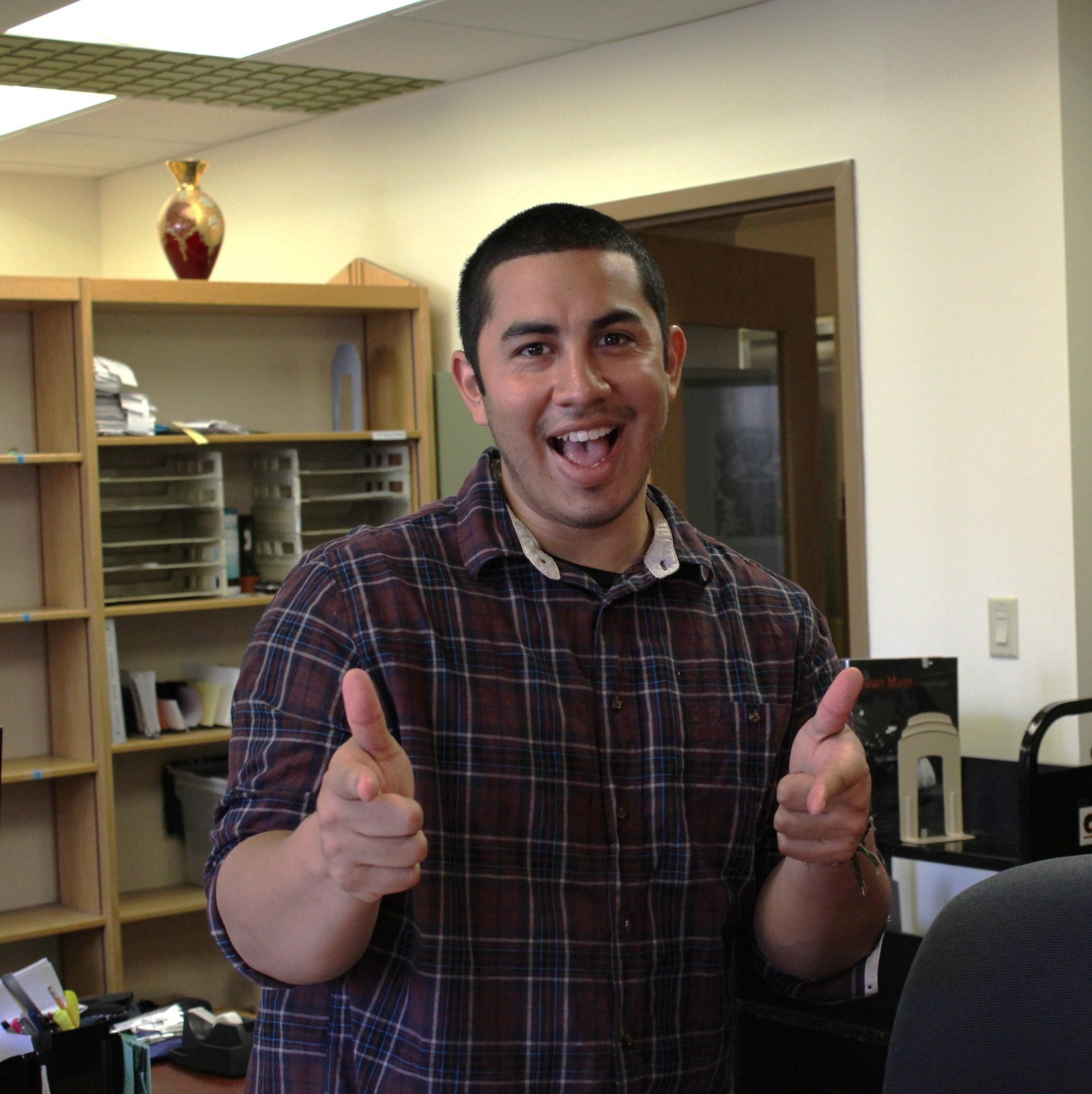 Photo of a male student worker with two thumbs up at the Library's main desk