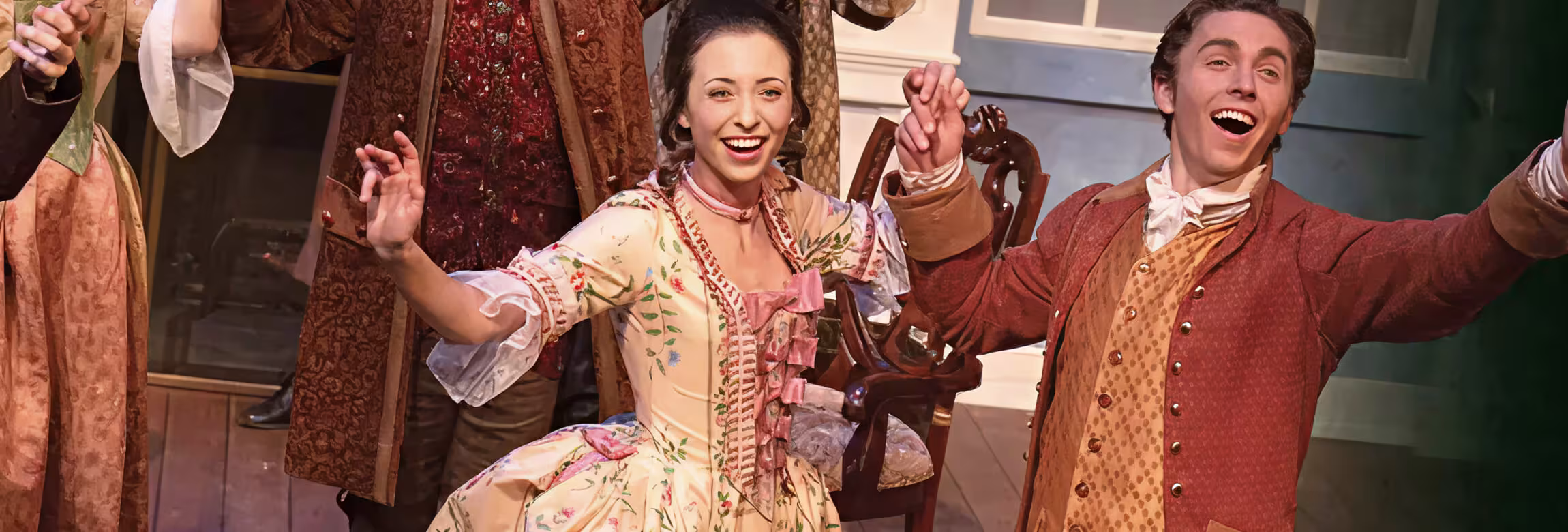 scene from production: women and man holding hands and smiling on stage