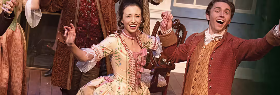 scene from production: women and man holding hands and smiling on stage